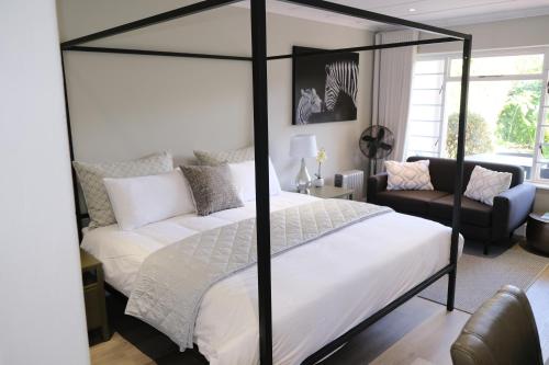 a bedroom with a four poster bed and a couch at High Hedges Guest Suites Constantia in Cape Town