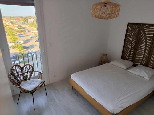 une chambre avec un lit, une chaise et une fenêtre dans l'établissement Appart lumineux et climatise St Cyprien plage, à Saint-Cyprien