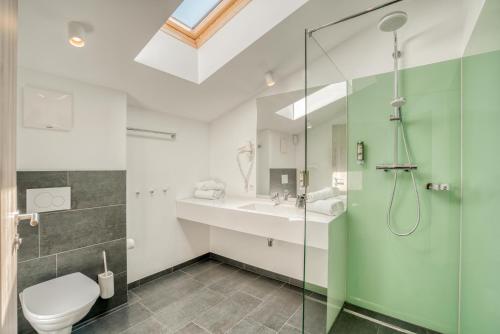 a bathroom with a shower and a toilet and a sink at COOEE alpin Hotel Kitzbüheler Alpen in Sankt Johann in Tirol