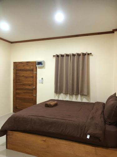 a bedroom with a bed with a wooden frame and a window at บ้านศรีสุธรรม 2 Baansrisuthum 2 in Surat Thani