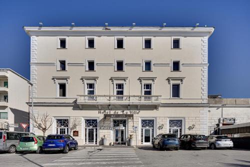 Un edificio blanco con coches aparcados delante. en Hotel De La Ville, en Civitavecchia