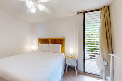 a white bedroom with a bed and a window at Maalaea Banyans 105 in Wailuku