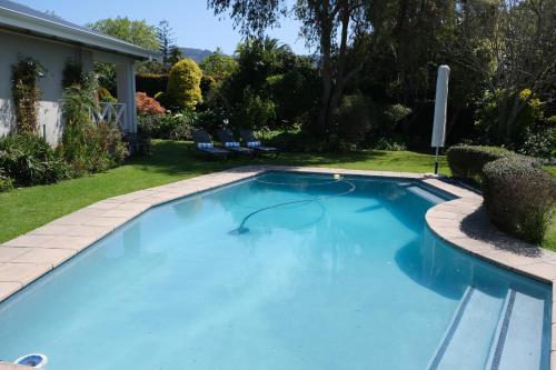 a swimming pool in a yard with a house at High Hedges Guest Suites Constantia in Cape Town