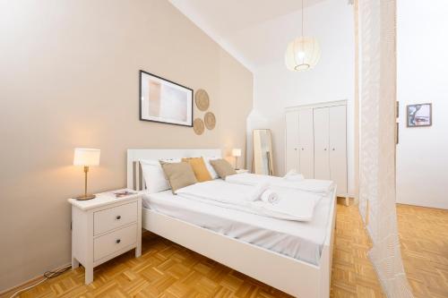 a white bedroom with a bed and a night stand at Spacious apartment in Graz for 6 people in Graz