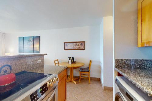 a kitchen with a stove top oven next to a table at Maalaea Banyans 105 in Wailuku