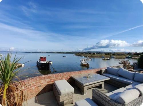 a patio with couches and tables and boats in the water at Luxury beachfront property Cockles-Sea View-private parking for 2 cars-sleeps 10 in Exmouth
