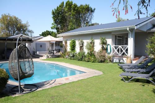 a yard with a swimming pool and a house at High Hedges Guest Suites Constantia in Cape Town