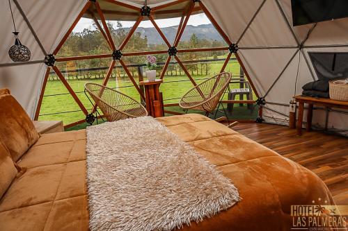 a tent with a bed and a table and chairs at Hotel Las Palmeras Gachancipa in Gachancipá