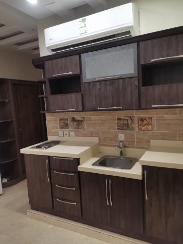 a kitchen with wooden cabinets and a sink at شقق مفروشه قارا in Qārā