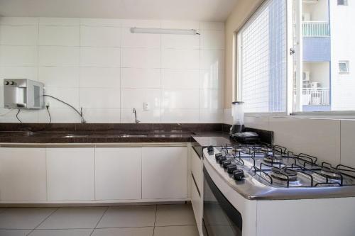 une cuisine blanche avec une cuisinière et un évier dans l'établissement PLT41 - Sacada Ampla com Churrasqueira, 3 Suítes, à Balneário Camboriú