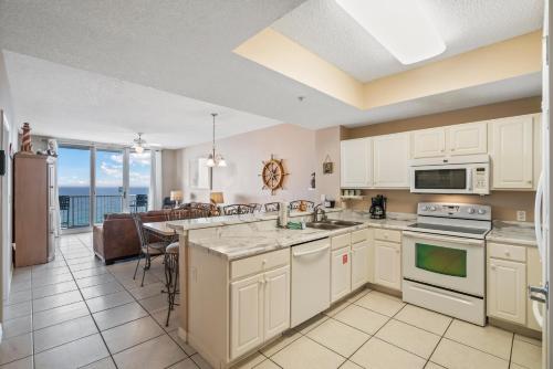 a kitchen with white cabinets and a dining room with a table at Summerwind West 1003 in Navarre