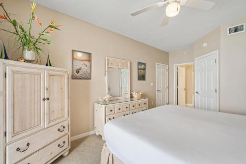a bedroom with a large white bed and a dresser at Summerwind West 1003 in Navarre