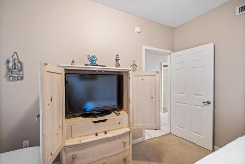 a tv on a wooden dresser in a bedroom at Summerwind West 1003 in Navarre