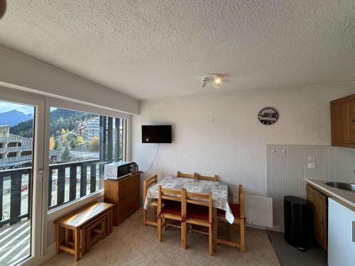 une cuisine avec une table et des chaises ainsi qu'une fenêtre dans l'établissement Appartement 6 couchages au pied des pistes avec balcon - Auris en Oisans - FR-1-297-108, à Auris