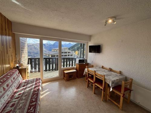 a living room with a table and a large window at Appartement 6 couchages au pied des pistes avec balcon - Auris en Oisans - FR-1-297-108 in Auris