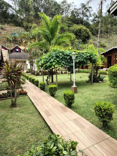 a wooden walkway in a garden with trees and houses at Pousada Mon Desir in Penedo