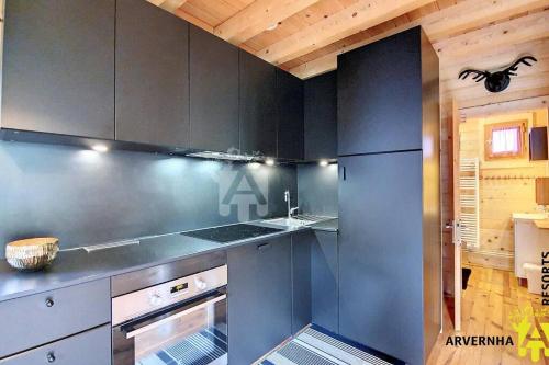 La cuisine est équipée de placards gris et d'un four avec plaques de cuisson. dans l'établissement Chalet de Cécile 1, à Besse-et-Saint-Anastaise