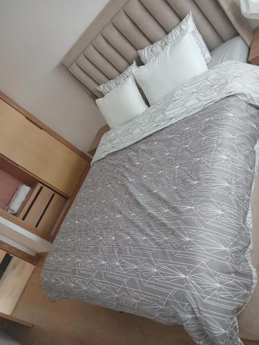 a bed with a gray comforter and pillows at Glorious NOUACEUR in Nouaceur