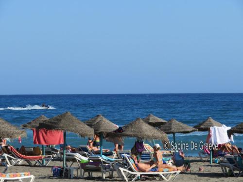 a group of people sitting on the beach with umbrellas at Ruselo in Torrox Costa