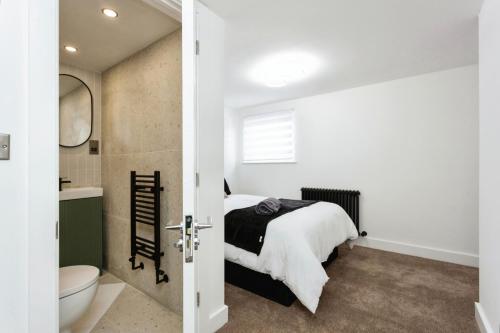 a bedroom with a bed and a bathroom with a toilet at Luxurious 10-Person Modern House with Garden in Central Tonbridge in Kent