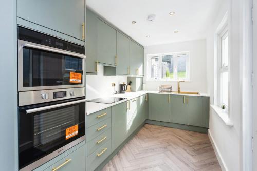 a large kitchen with green cabinets and appliances at Luxurious 10-Person Modern House with Garden in Central Tonbridge in Kent