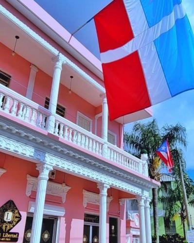 a pink building with an umbrella in front of it at Hotel Libertad in Lares