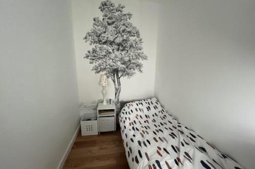 Cette chambre comprend un lit et un arbre sur le mur. dans l'établissement Duplex 10 minutes from the beach in Trouville, à Trouville-sur-Mer