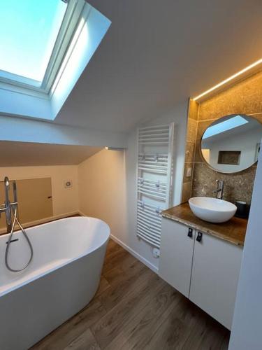 La salle de bains est pourvue d'une grande baignoire et d'un lavabo. dans l'établissement Maison Bordeaux Saint Émilion, à Beychac-et-Caillau