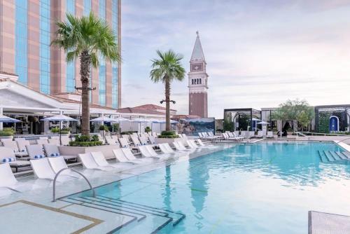 a swimming pool with chairs and a clock tower at The Palazzo at The Venetian Resort by Suiteness in Las Vegas