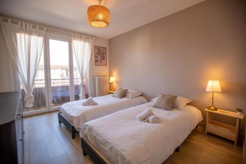 une chambre avec deux lits et une grande fenêtre dans l'établissement Le Cygne - vue montagne - proche du centre ville, à Annecy