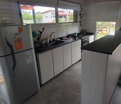 una cocina con electrodomésticos blancos y encimeras negras en Monchos House, en Merlo