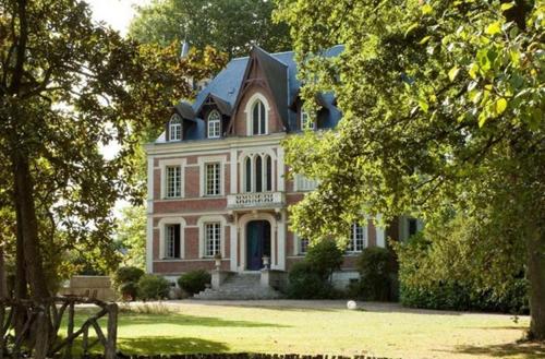 uma grande casa branca com um telhado preto em Maison d'hôtes Le Manoir de Contres em Contres