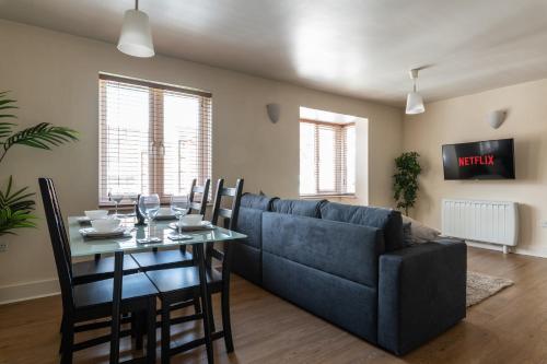 a living room with a blue couch and a table at Spacious 2BR Flat - 2 Free Parking Spaces - Near LGW Airport in Crawley