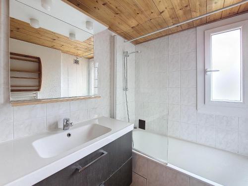 La salle de bains est pourvue d'un lavabo, d'une baignoire et d'une fenêtre. dans l'établissement APPARTEMENT PROCHE REMONTEES MECANIQUES - WIFI - MORZINE - 7 PERSONNES - JOUX 7, à Morzine