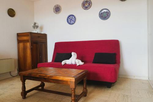 - un canapé rouge avec un chien blanc assis dans l'établissement Port Pêche 4 Pers Terrasse vue mer Parking privé, au Barcarès