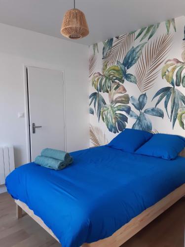 - une chambre avec un lit bleu et un papier peint tropical dans l'établissement Le Garde-Côtes, à Étel