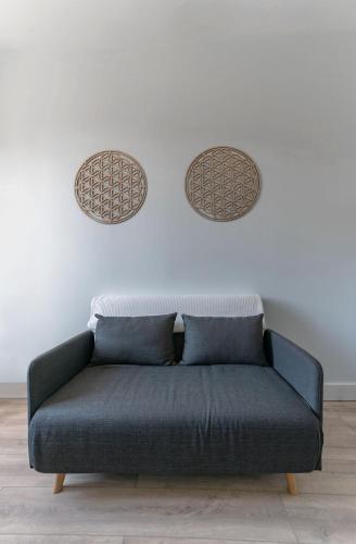 a blue couch against a white wall with two mirrors at Le Petit George V - Appartement design proche Thermes in Vichy