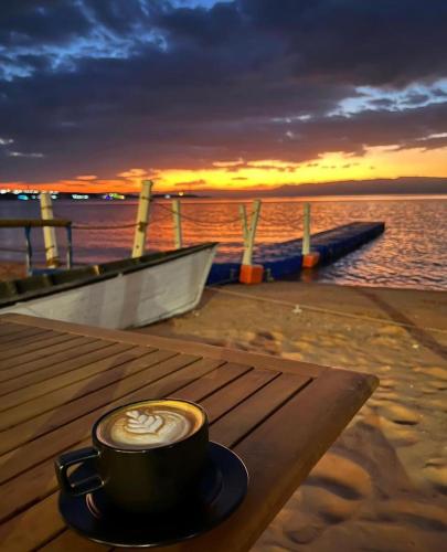 a cup of coffee sitting on a wooden table near the water at فندق حياة حقل الفندقية Hayat Haql Hotel in Al Humaizah