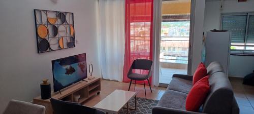 Una sala de estar con un sofá y un televisor. en NANA -Grand Appartement Cosy- C 43- Cuisine équipée-CLIM-WIFI-Terrasse, en Cayenne