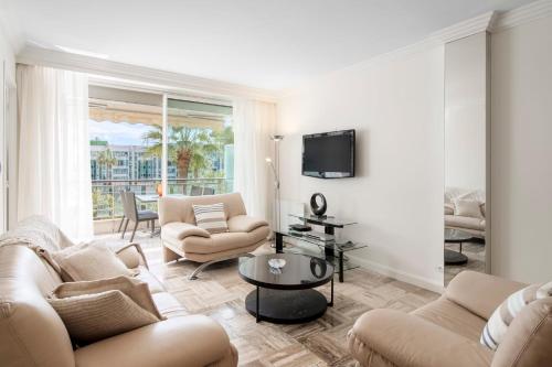 un salon avec deux canapés et une télévision dans l'établissement REF 30 - Cannes Croisette - Sea and gardens view apartment for rent, à Cannes