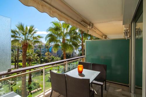 un balcon avec une table, des chaises et des palmiers dans l'établissement REF 30 - Cannes Croisette - Sea and gardens view apartment for rent, à Cannes