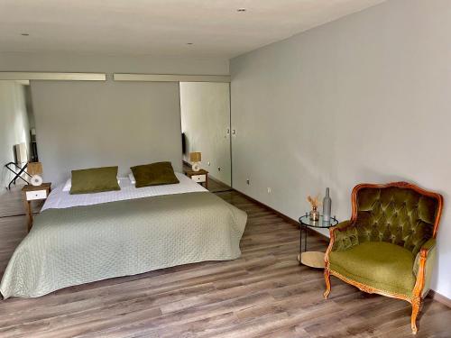 a bedroom with a bed and a chair at Hotel Joly in Armentières