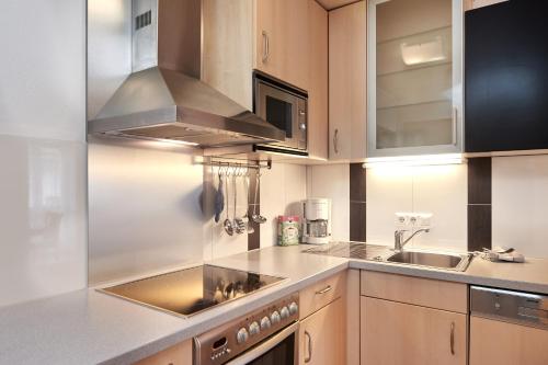 a kitchen with wooden cabinets and a sink at Pension Vorberghof- Bauernhofurlaub in Ramsau am Dachstein
