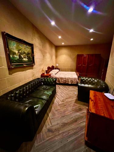 a room with two beds and leather couches in a room at Dreamy space with caved pool in Ħofret ir-Rizz