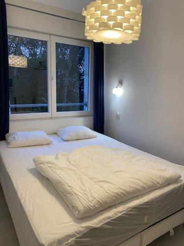 une chambre avec un lit blanc avec une fenêtre dans l'établissement La clairière Merlimont, à Merlimont