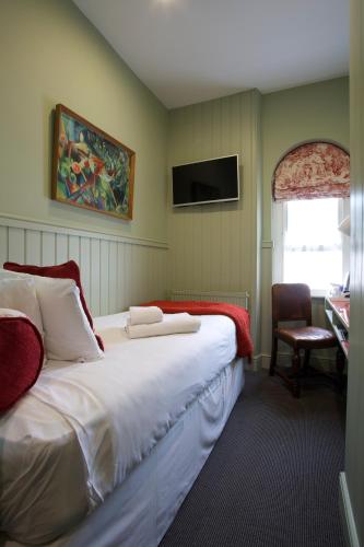 a bedroom with a bed and a desk and a television at Georgian House Hotel in London