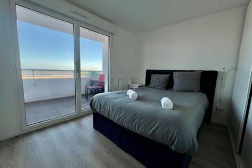 une chambre avec un lit et une grande fenêtre dans l'établissement Le Panoramique vue mer, à Dunkerque