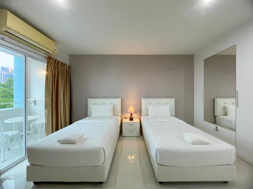 two beds in a room with a window at Baan Pattaya by Sabai in Pattaya Central