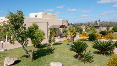 a garden with palm trees and a building at Delle Rose, Hotel & Horse Riding in Torre Vado
