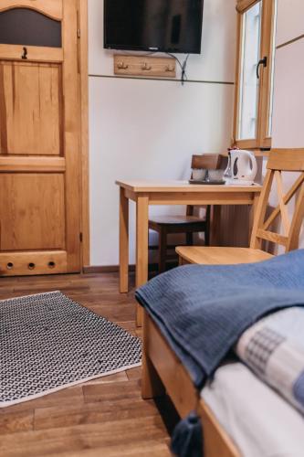 a room with a bed and a table with a television at Villa Hubertus in Srebrna Góra